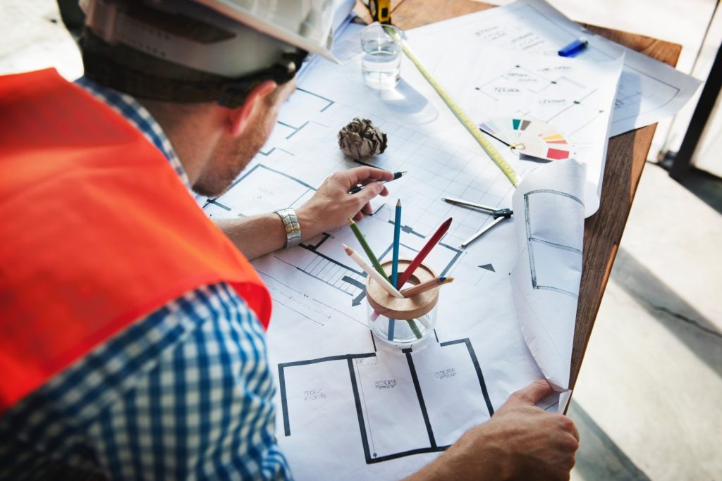 an engineer bends over blueprints of a building