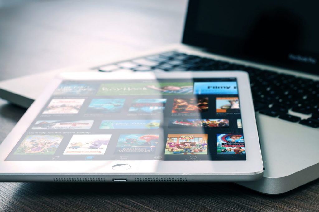 a tablet lying on top of a laptop computer.