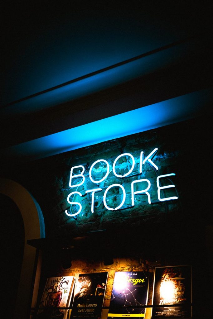 a neon sign reading'book store' above a display of books