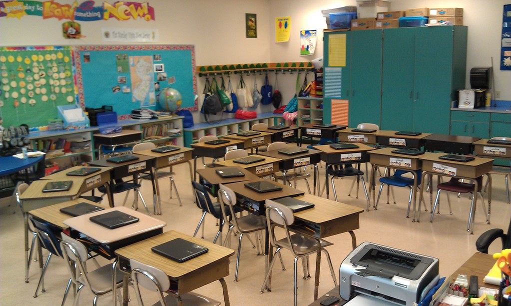 an empty classroom with a a device sitting on each desk