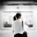 a woman stands before a moving train