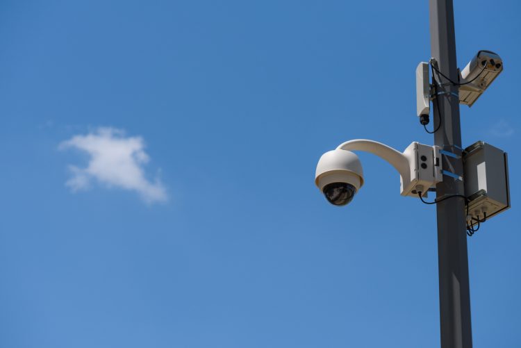 a surveillance camera mounted on a pole before a blue sky