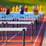 A selective focus shot of a high school track event hurdles race in progress