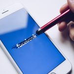 A person draws over the Facebook logo on a mobile device.