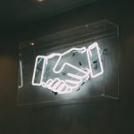 a neon sign depicts two hands shaking