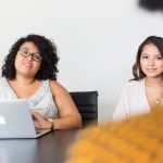 Three students sit around a desk discussing.