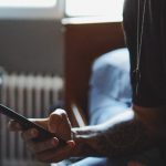 A student checks their smartphone in their bedroom.