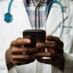 A doctor holds a smartphone.