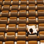 overhead shot of a lone student in an otherwise empty lecture hall