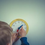 A kid plays with a clock learning tool.