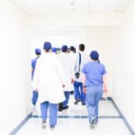 A group of medical professionals walk a gurney down a hallway.