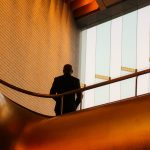 A businessman is silhouetted in front of an orange corporate interior