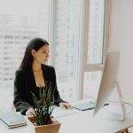 A woman sits in an office in front of her computer.