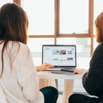 Two learners sit in front of a laptop