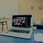 A computer with a zoom meeting stands open in a classroom