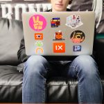 A young person works on their laptop sitting on a couch.