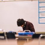 A student sits in a classroom bent over work.