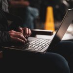 A person works on a laptop while sitting in a chair.