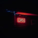 A neon open sign hangs outside a restaurant.
