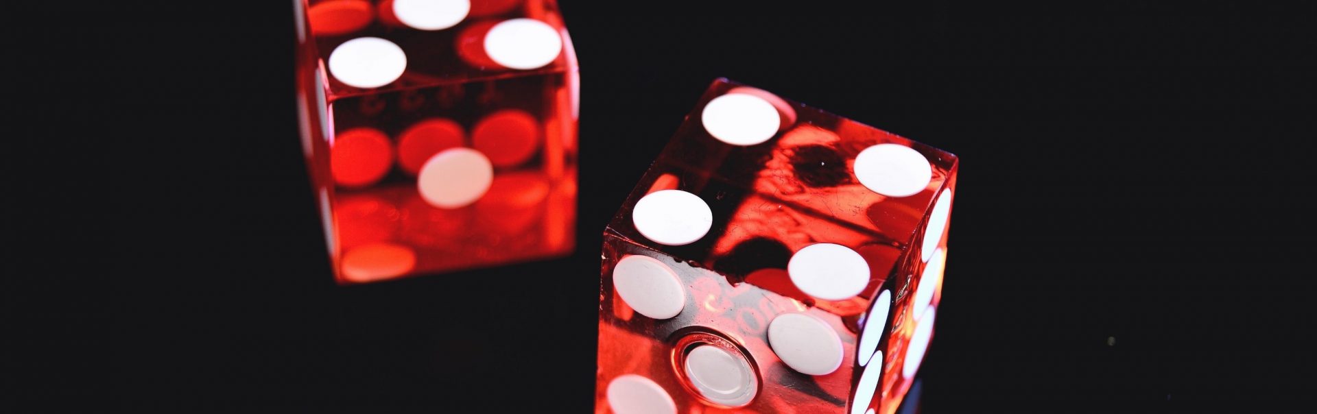 Two red dice sit on a black table.