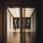 A student is mirrored as he walks down a school hallway.