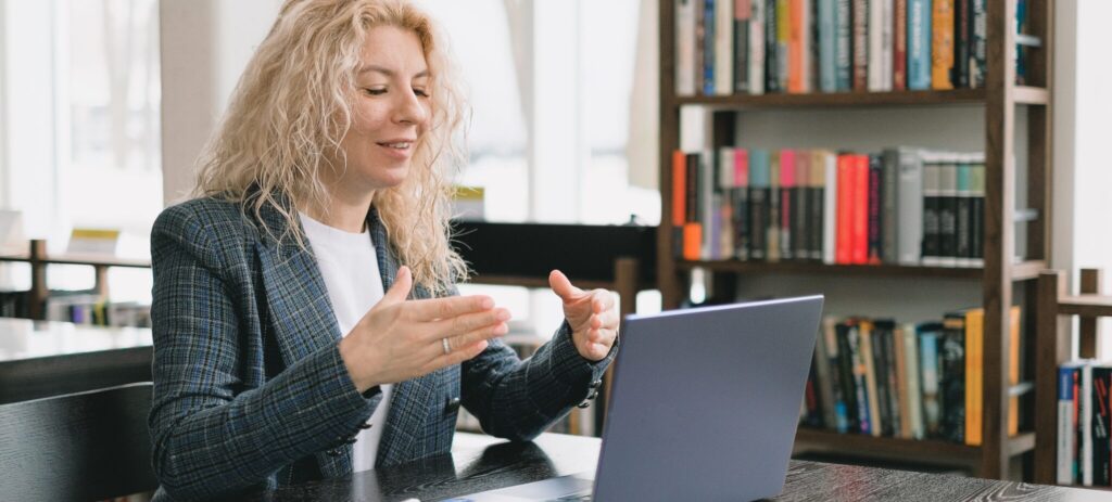 Smiling woman having video chat via laptop in library.