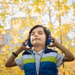 Child in the woods wearing headphones.