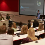 Young adult students at a university lecture, back view