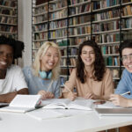 Portrait of four multi ethnic students studying in library