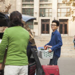Young man moving into dormitory on college campusa woman.